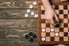 hands playing checkers on a wooden table