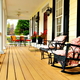 A classic front porch with a rocking chair and several other chairs for seating.