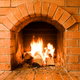 A brick masonry fireplace with a lit fire.