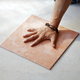a hand pressing a tile down on the ground