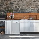 outdoor kitchen area with stainless steel cabinets and grill against stone wall