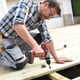 man building a wood deck with a drill gun