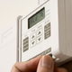 A homeowner adjusting the settings on a digital thermostat.