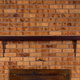 A wooden mantel on a brick fireplace.