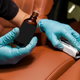 hands with essential oil bottle cleaning car upholstery