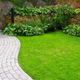 landscaped yard with curved walkway, grass, and bushes