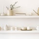 floating shelves with simple ceramic items and brass watering can