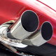 The shiny chrome exhaust of a red car.