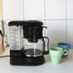 a coffeemaker on the counter with cups nearby