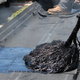 applying hot roofing tar with a mop