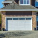 Home with white garage door and stone cladding accents