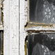 An old window frame with peeling paint and rotting wood.