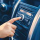 A finger pushing a button on a car radio. 