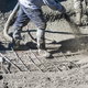 worker spraying concrete mixture to form the base of a pool