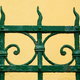 A wrought-iron gate with a spotty coat of green paint.