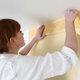 A woman installs wallpaper trim.