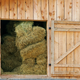 a stack of hay inside a barn with the door open