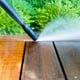 pressure washer cleaning dirt off a wooden patio