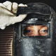 A female welder lifting up the guard on her welding mask.