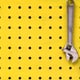 yellow painted pegboard with hanging wrenches