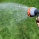 hand holding spray hose pointed at lawn