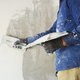 A man applying white putty to a wall. 