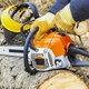 person with safety gloves and chainsaw by cut tree