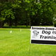 An Invisible Fence brand Dog in Training placard sign on a suburban residence front lawn.