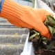 gloved hand cleaning leaves from gutter
