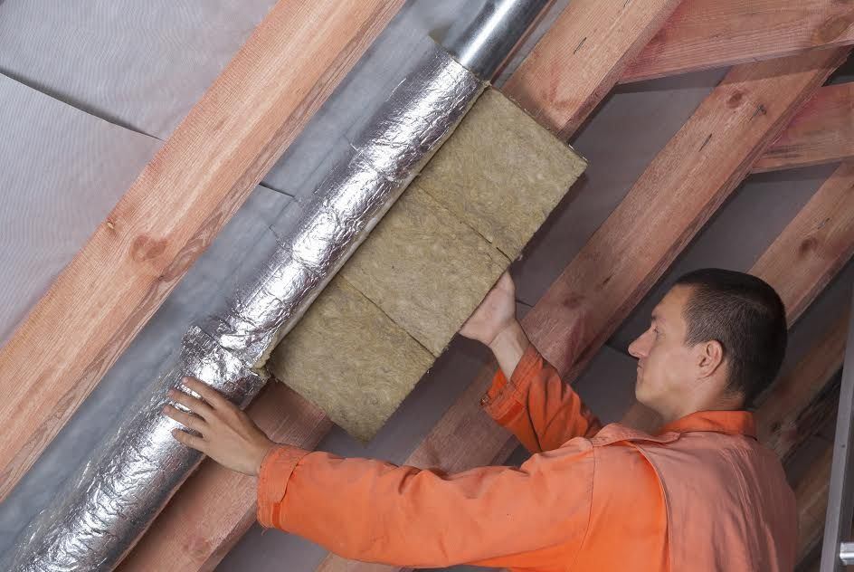 A man insulating a ventilation pipe. 