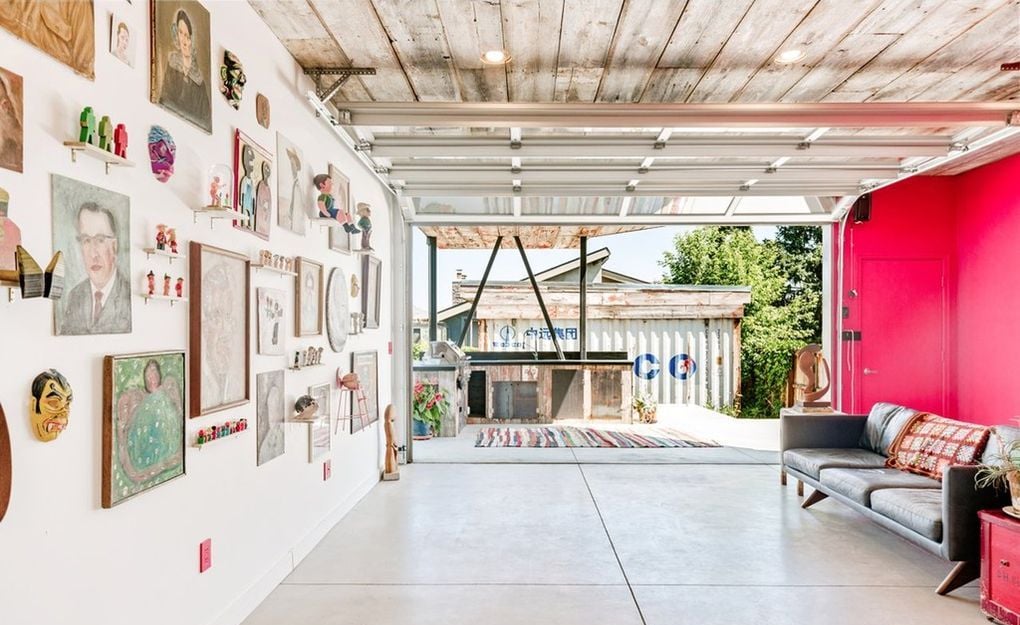 A large garage door in the shipping container's opens up to a gorgeous wooden outdoor patio.