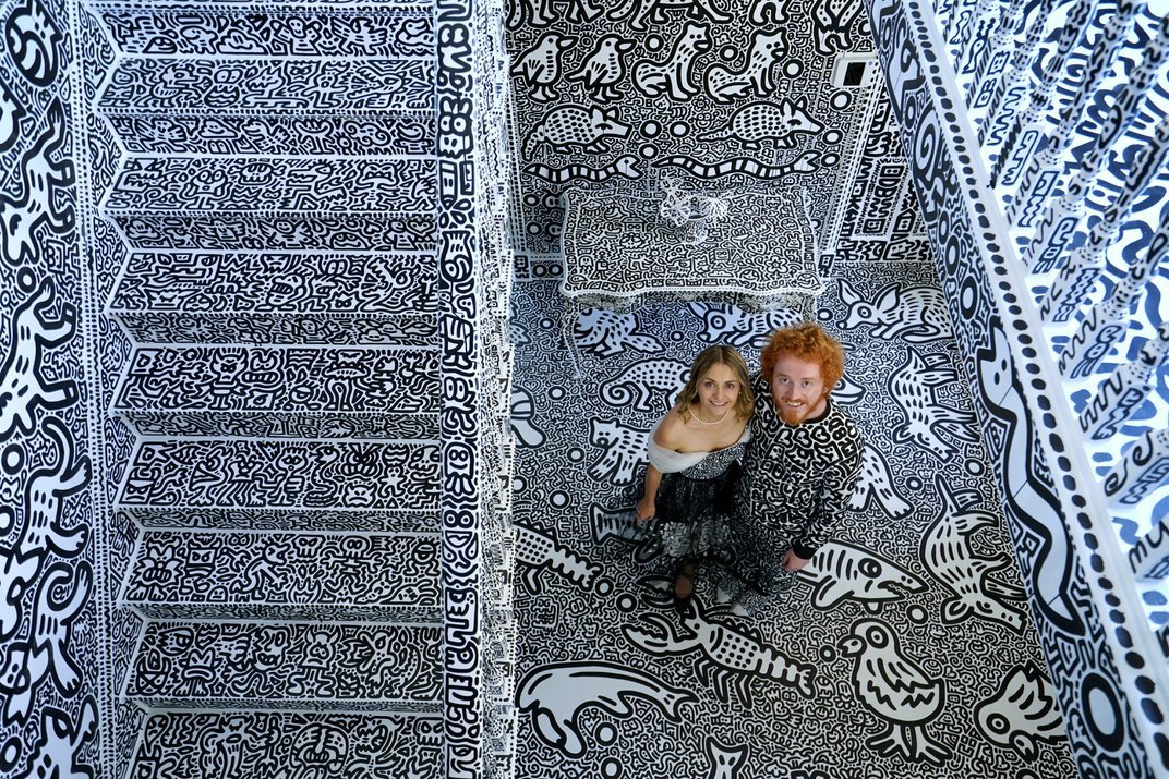 Sam and Alena Cox (aka Mr. and Mrs. Doodle) look up from the ground floor of their doodle-covered mansion in Kent, England. 
