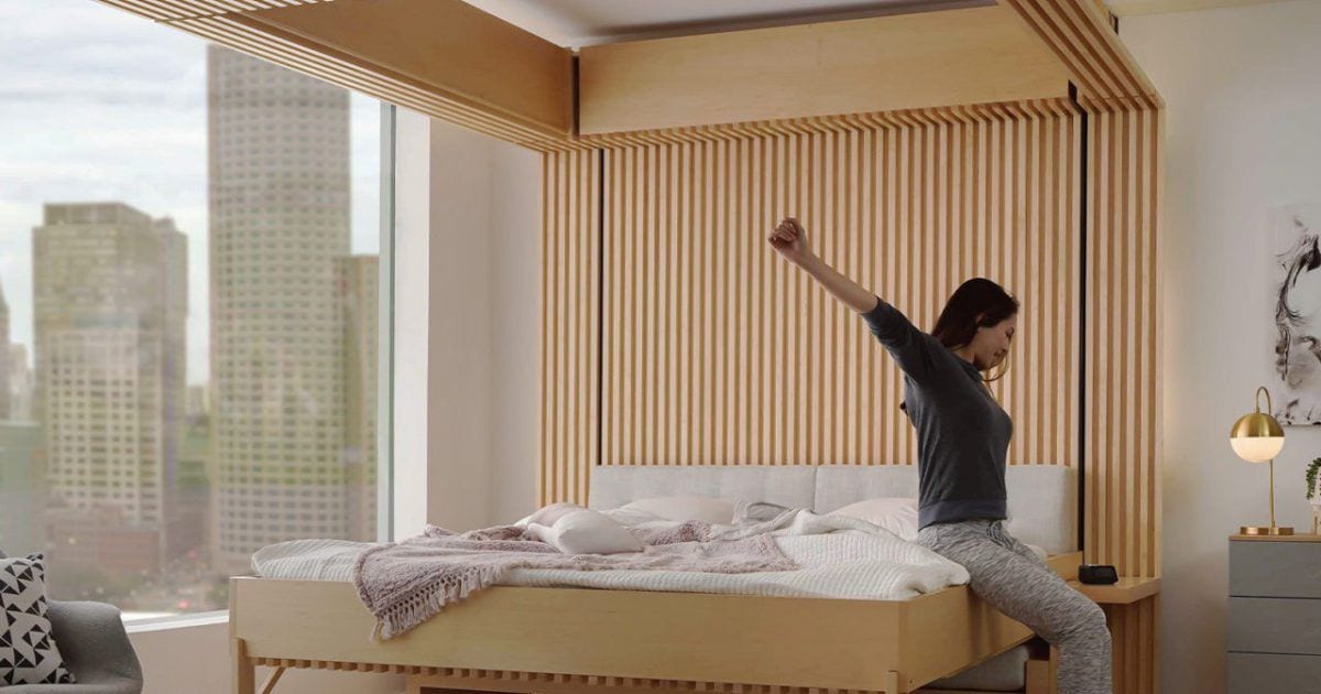 Woman greets the day from the comfort of her transforming Cloud Bed: Table Edition from Ori.