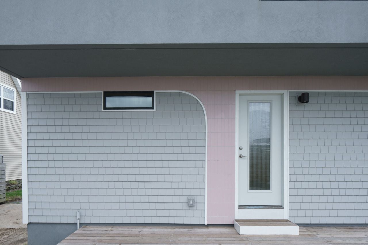 Soft pink tiles drag down from the House on House addition onto the facade of the original structure.