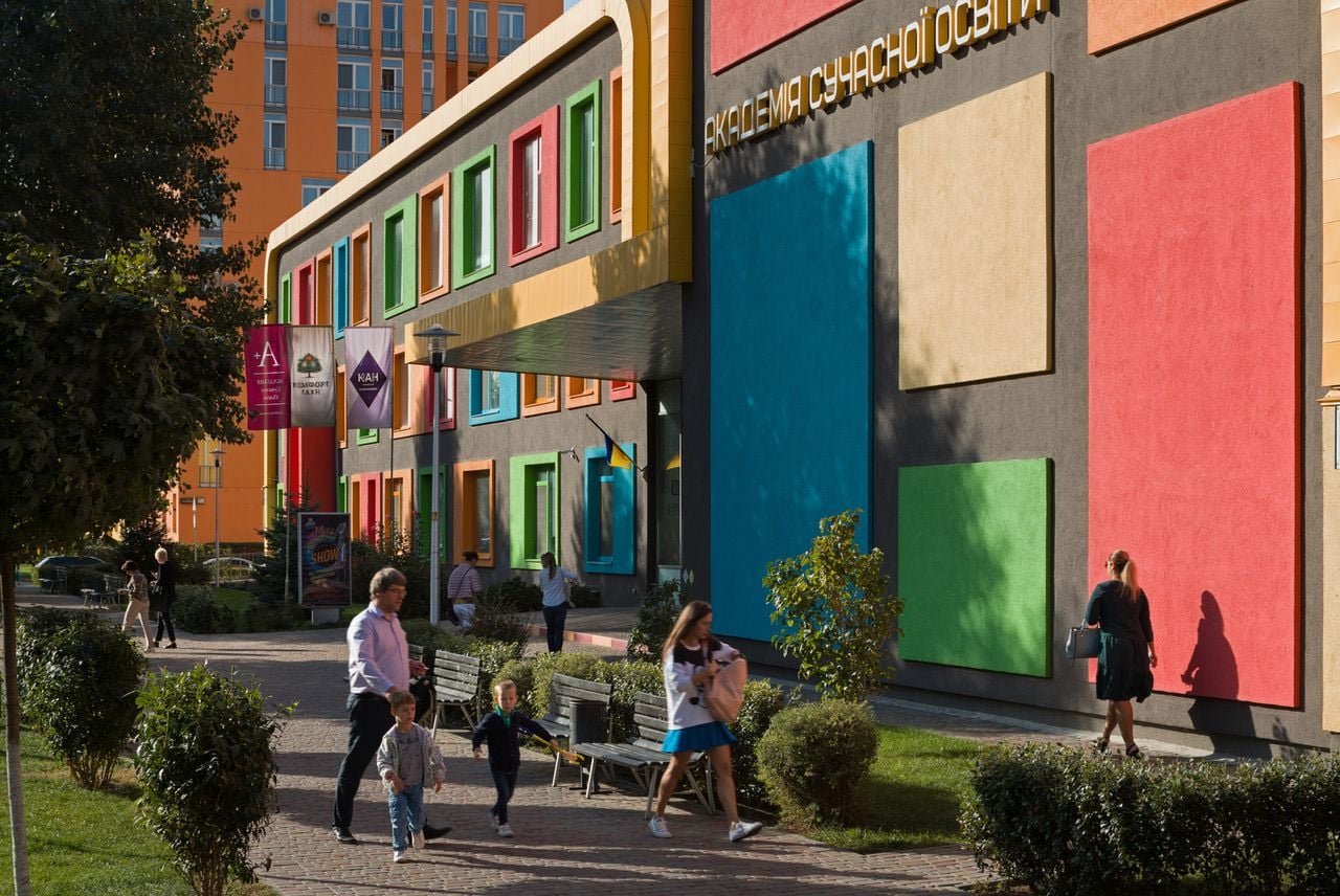 Pedestrians walk in and out of colorful ground-level shops built into the Comfort Town housing development.