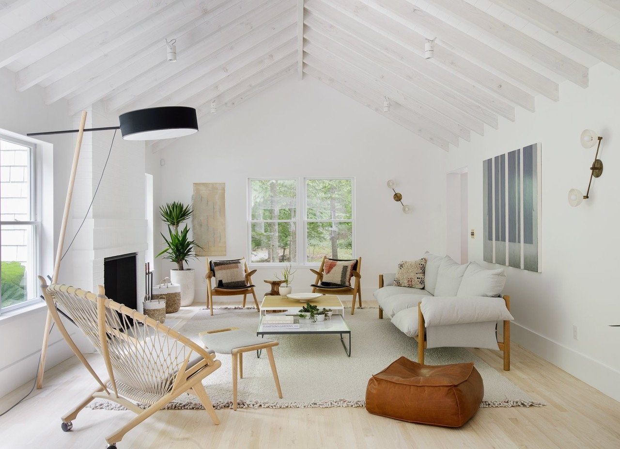 A spacious, white living room accented by lots of beachy Hamptons style decor pieces.