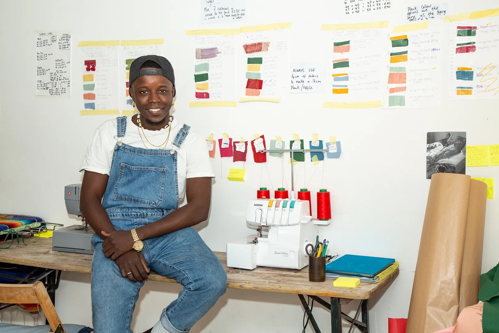 Paboy Bojang sits beside his sewing machine and workstation.