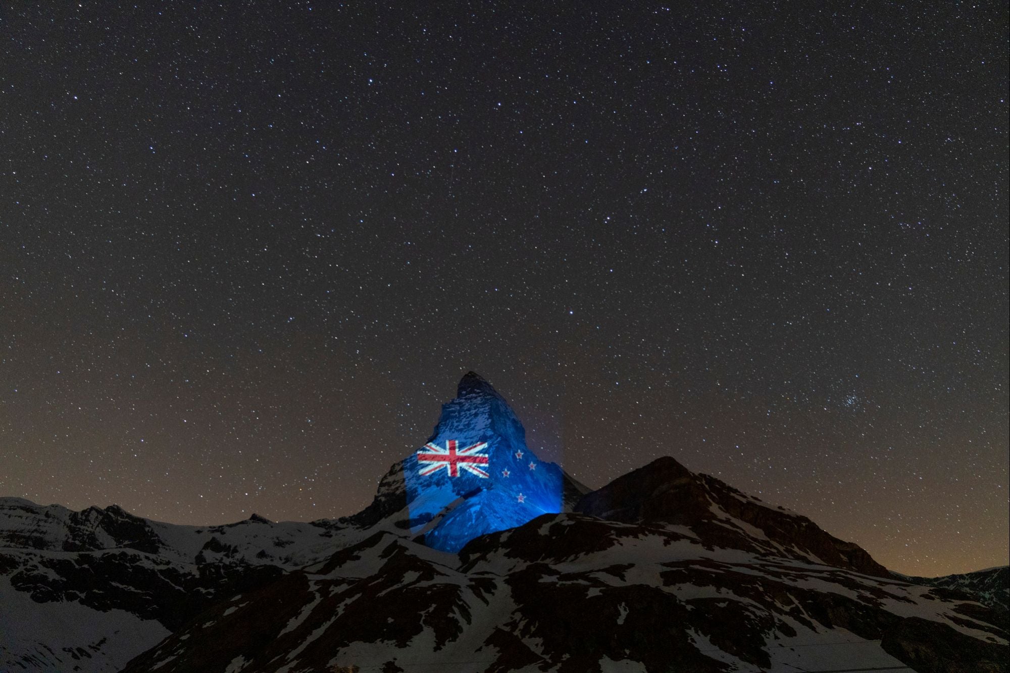 The lush blue Australian flag lights up the Matterhorn in the dead of a starry night. 