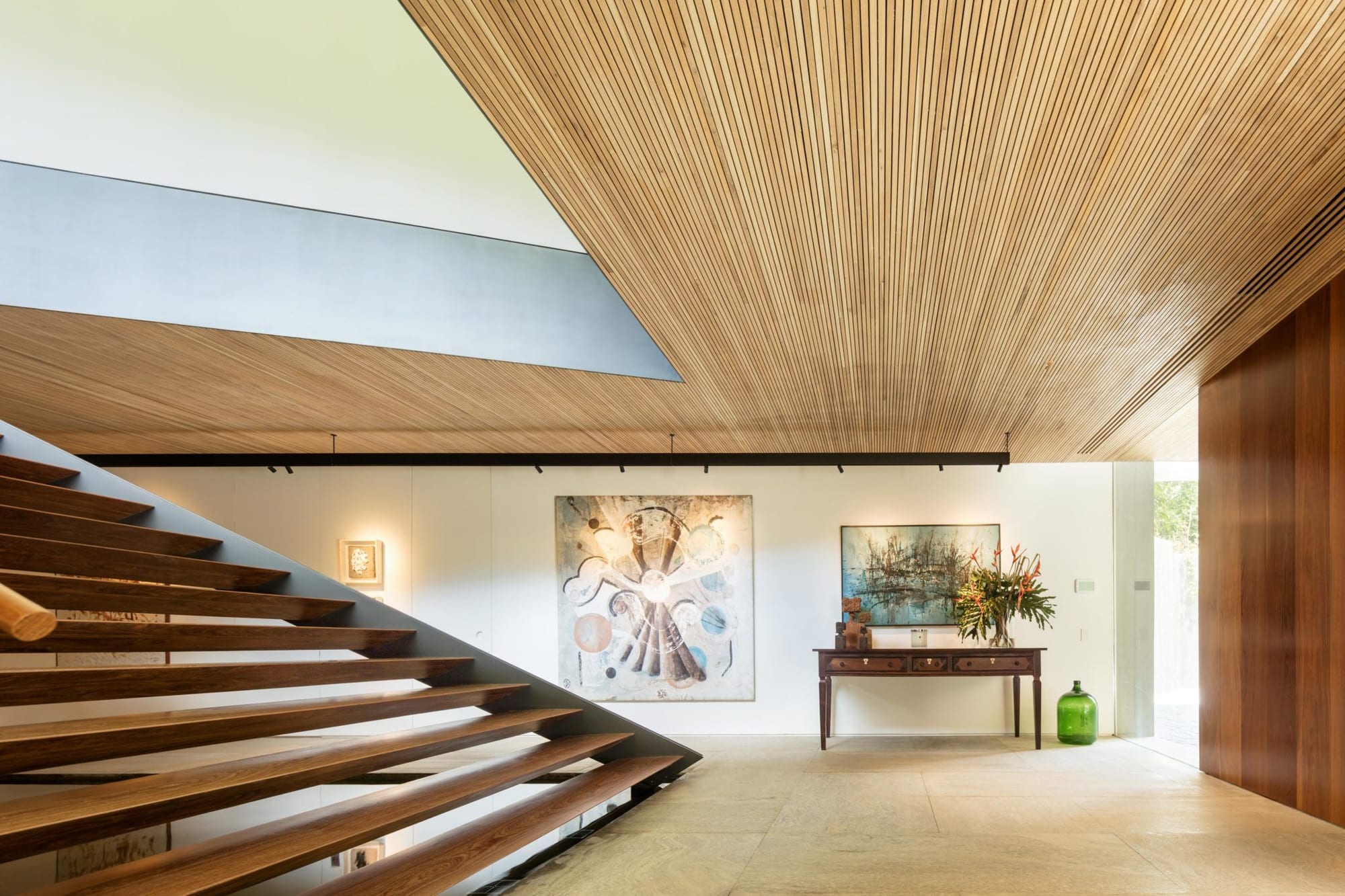 Spacious foyer/entryway inside the Bernardes Arquitetura-designed Asa House, adorned with timber slats in the ceiling and granite floors.