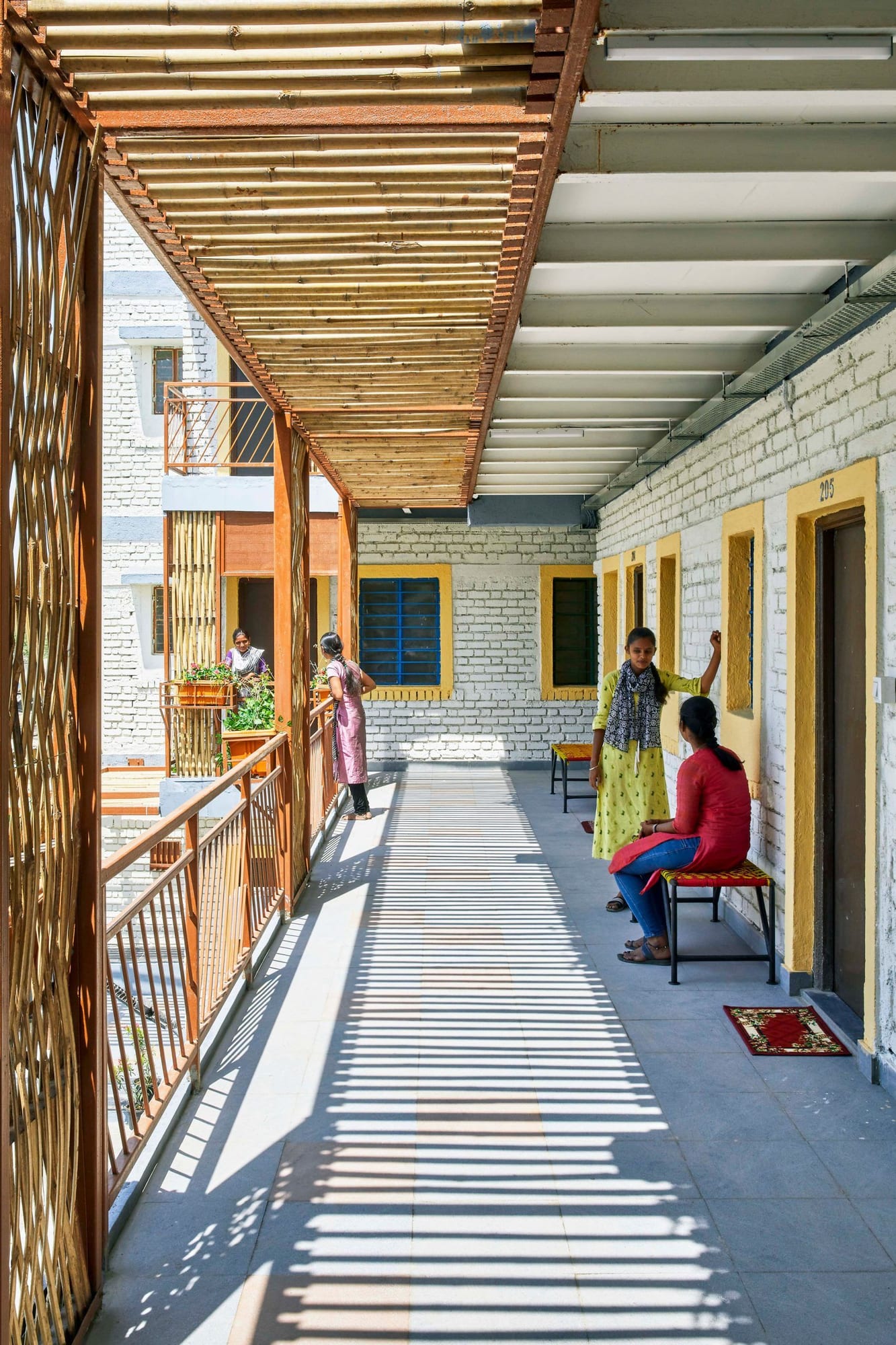 Residents mingle and look out over the surrounding area from the upper walkway of a CDA-designed affordable housing unit.