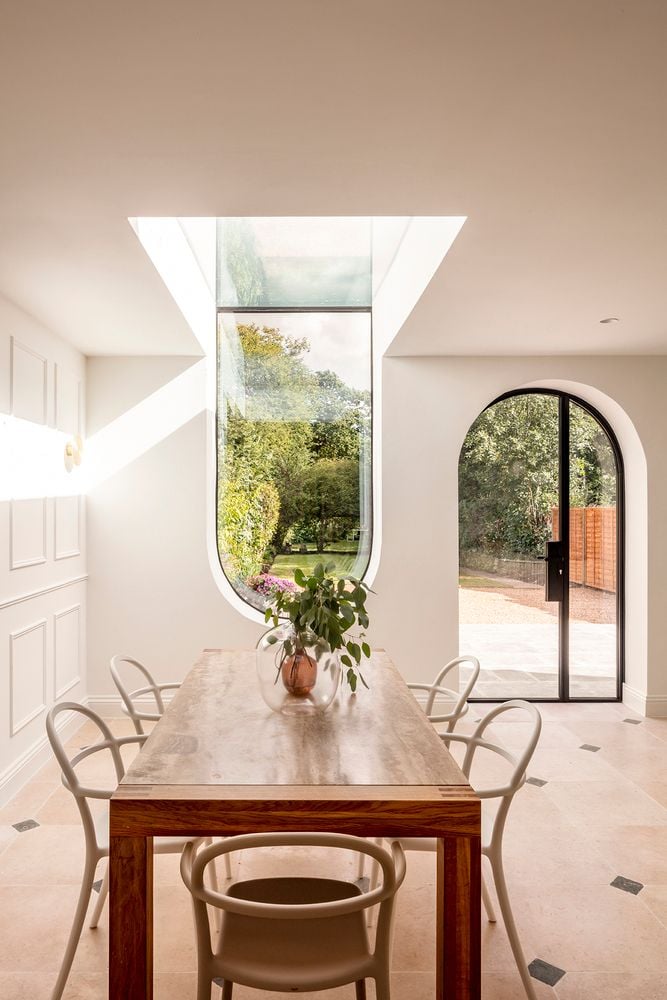 Simple dining room table in the remodeled nnU House kitchen sits in front of a large U-shaped window.