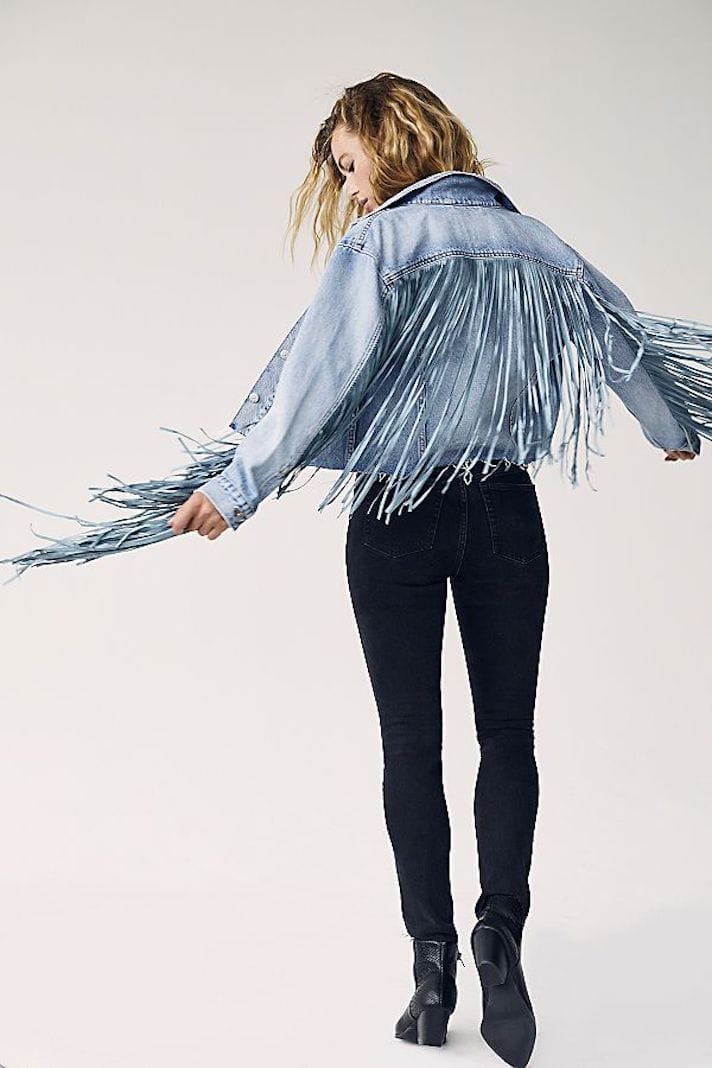 A young woman dawns a long fringe jacket.