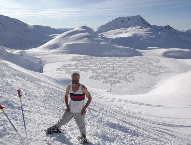 Simon Beck stands alongside one of his large-scale works of geometric snow art. 