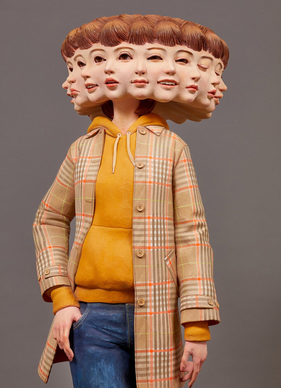 Surreal sculpture of a girl with 8 faces, carved and painted by Yoshitoshi Kanemaki.