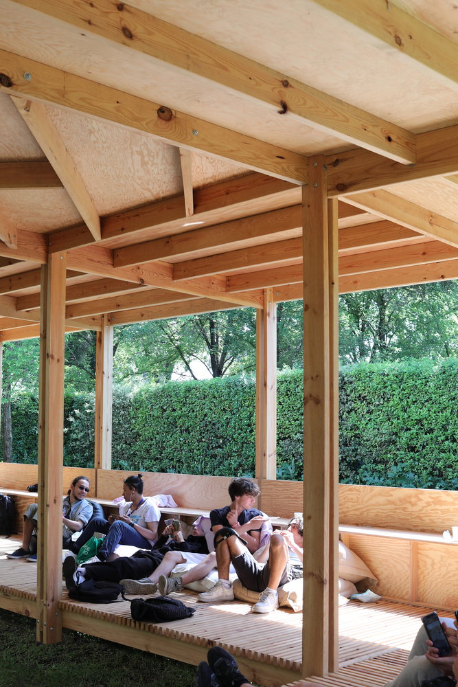 People sit and mingle on the timber slats that form the base of Rome's ProtoCAMPO Pavilion.