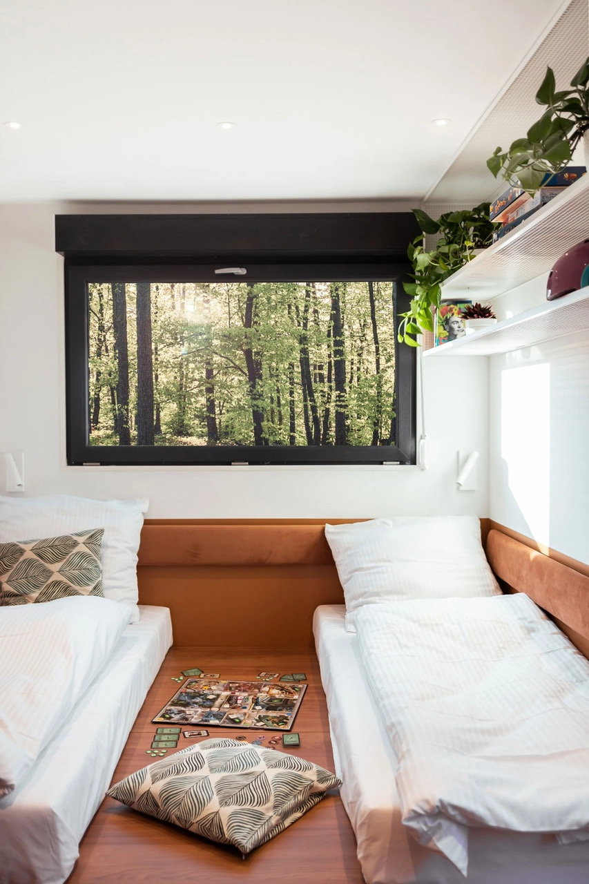 Close-up of the sleeping area inside Good Spot's upcycled mobile trailer, making abundant use of browns, whites, and natural light.