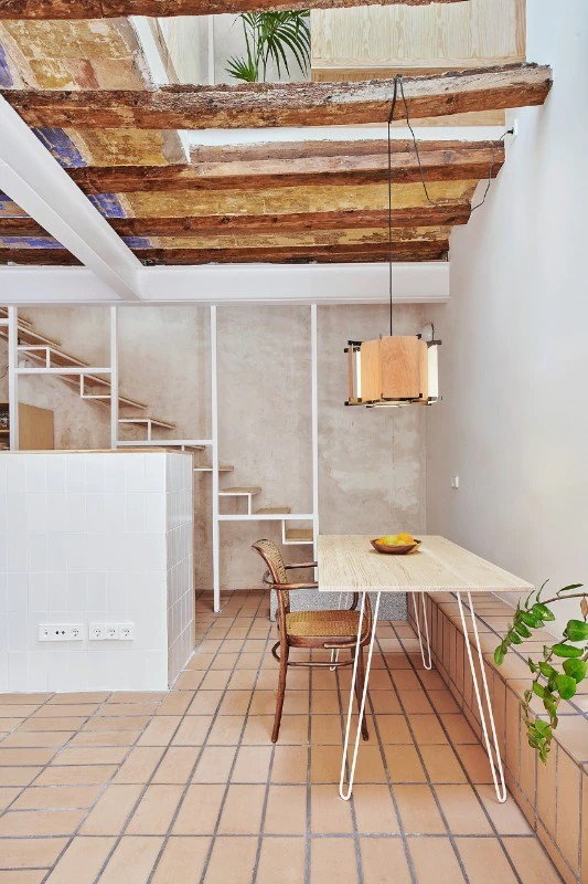 Small dining table sits in front of the exposed central stairway in the Twobo-restored 5x5-meter Barcelona home.