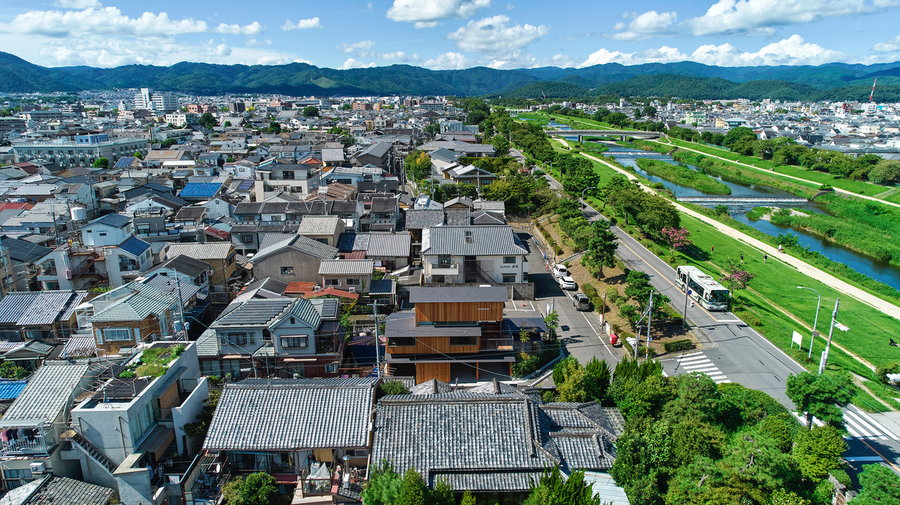 Zoomed out view shows the combination of deteriorating old-fashioned townhouses and new mansions around the multi-level House in Shimogamo.