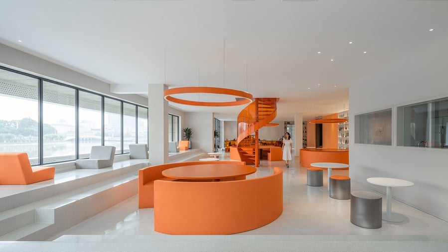 Modern lounge area with splashes of orange inside Wutopia Lab's cloud-inspired Duoyun bookstore.