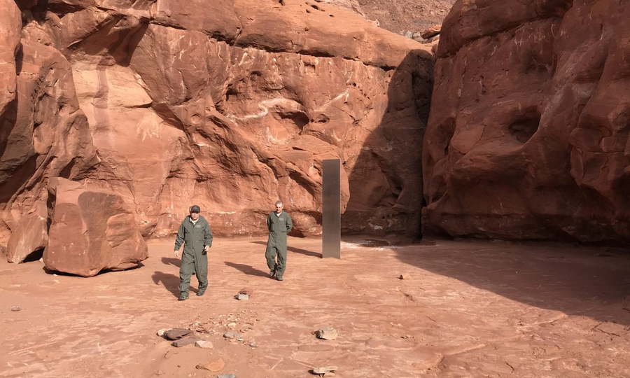 Two men stand near a mysterious monolith recently discovered in the Utah desert.